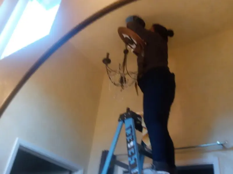 Electrician installing a chandelier in a Mokena residence